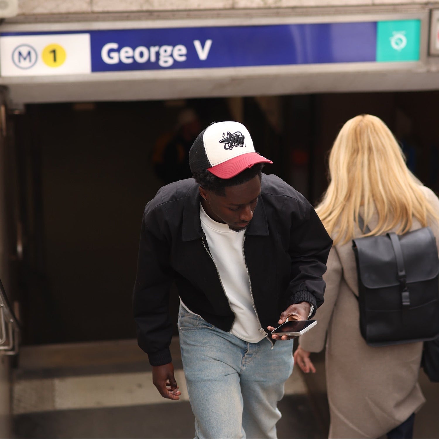 Two people walking through a subway station with a sign indicating 'George V'.
